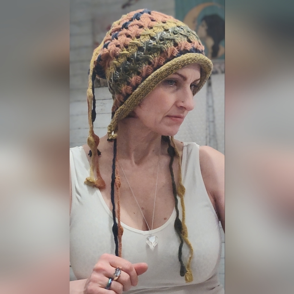 hand-crocheted multicolor beanie with ear flaps and tassel details.